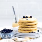 five vegan lemon blueberry pancakes stacked onto white plates.