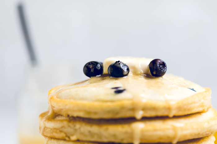 vegan lemon blueberry pancakes with fresh blueberries and lemon drizzle. 