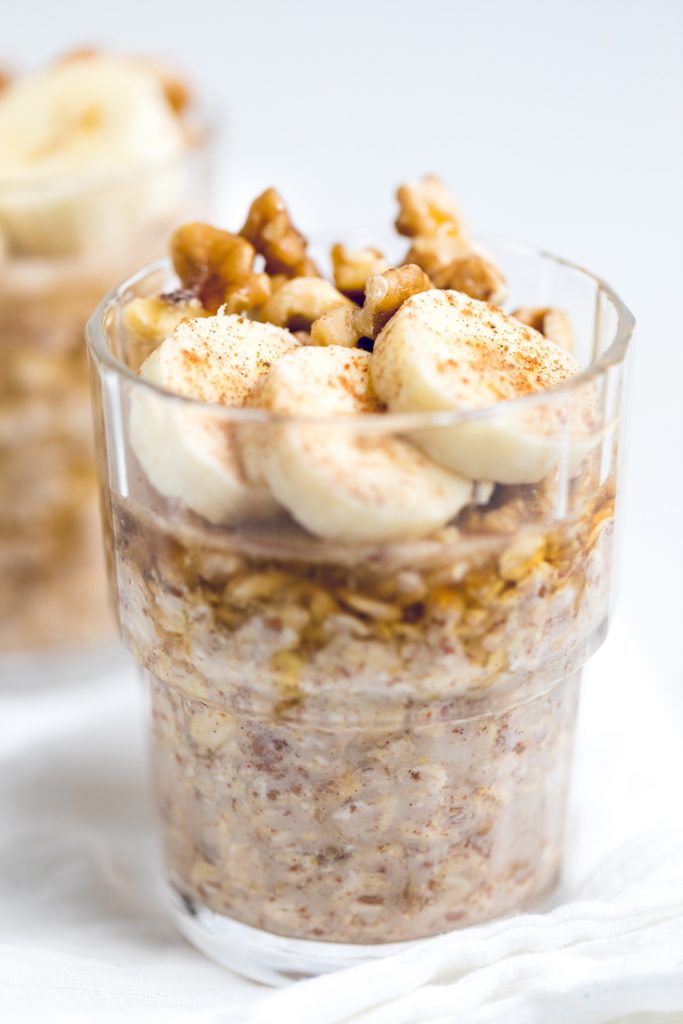 vegan banana bread overnight oats in a glass jar with bananas and nuts.
