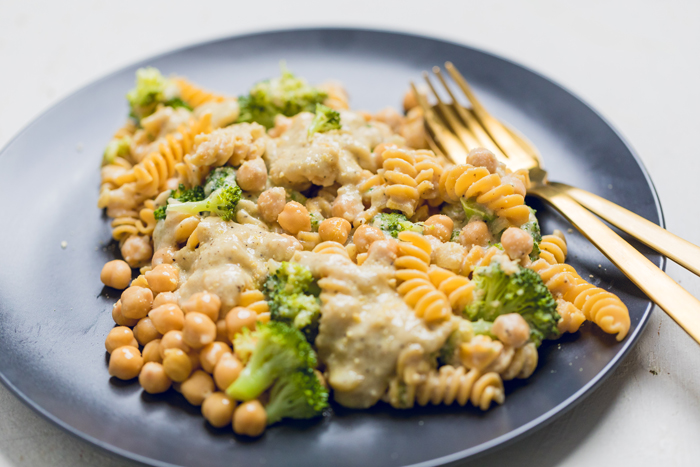 a plate of vegan creamy broccoli and chickpea pasta with extra sauce on top.