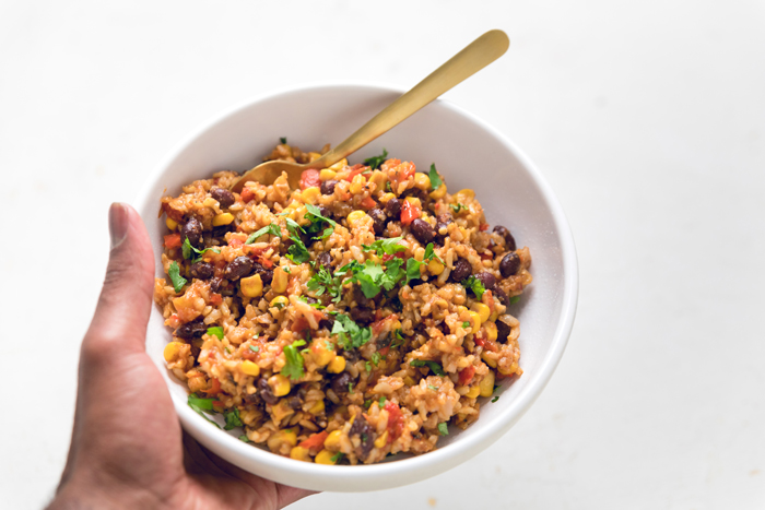 A hand holding a bowl of vegan instant pot tex-mex rice.