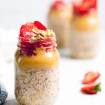 Vegan peanut butter and jelly overnight oats in a mason jar with fresh strawberries and peanuts.