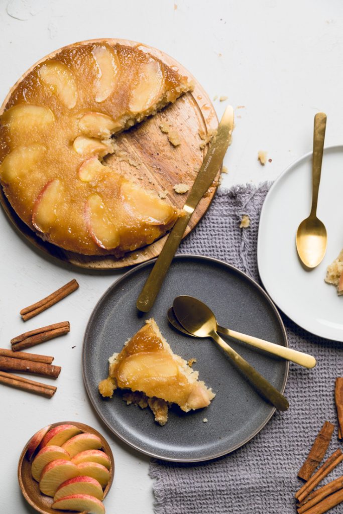 a board of vegan apple upside down cake with two plates with pieces on the side.