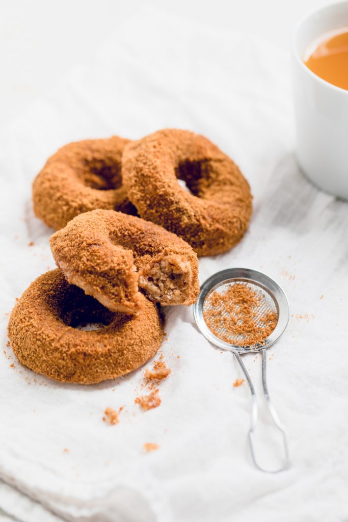easy baked vegan apple cider donuts on a table with a bite out of one.