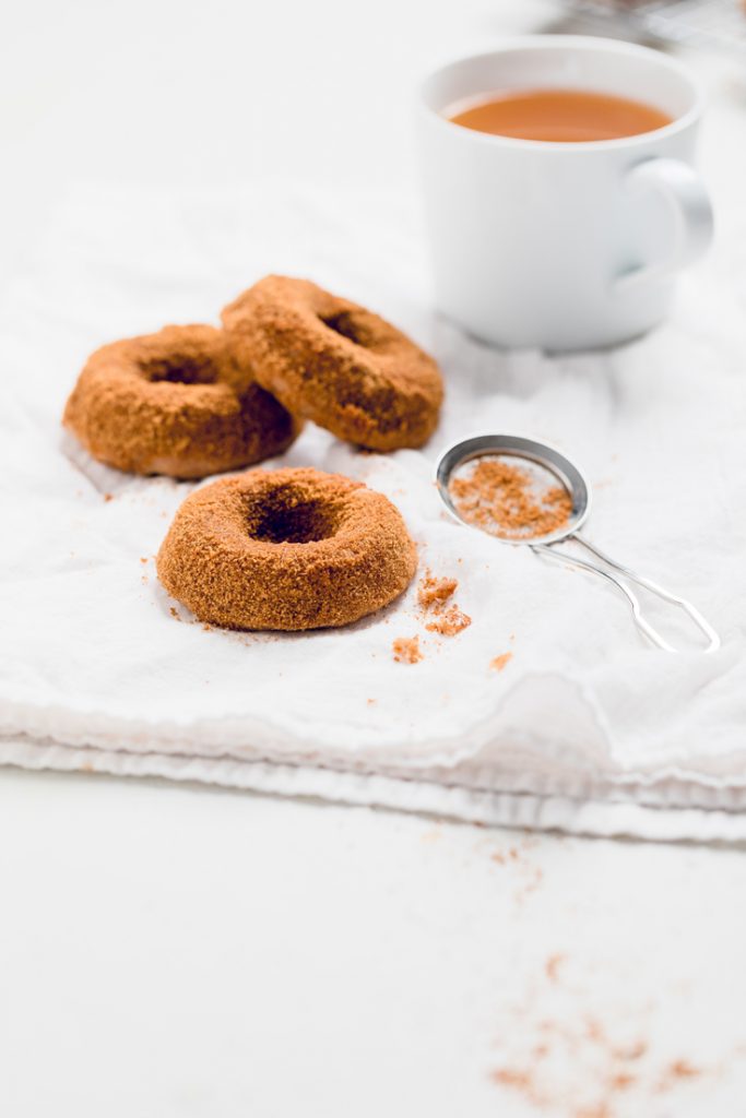 three easy baked vegan apple cider donuts on a table.