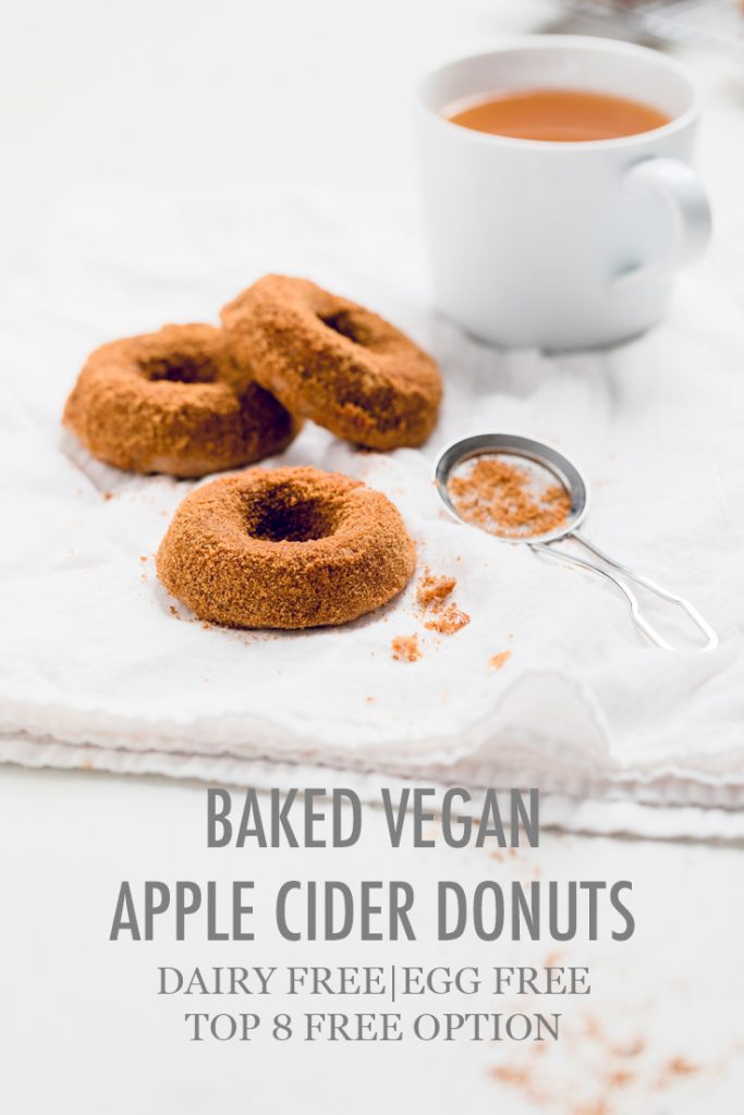 the words baked vegan apple cider donuts overlayed on a table of donuts.
