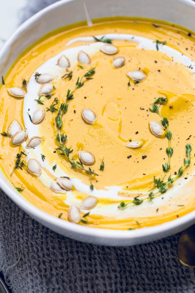 bowl of butternut squash soup with fresh thyme and a coconut drizzle 