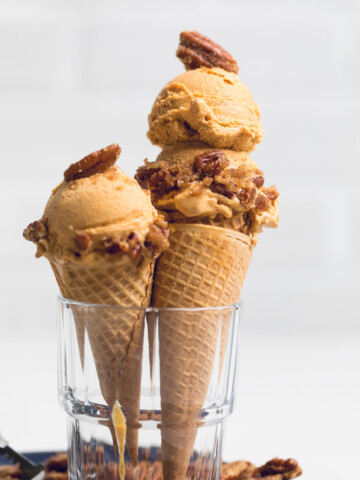 two vegan pumpkin ice cream in cones in a glass.