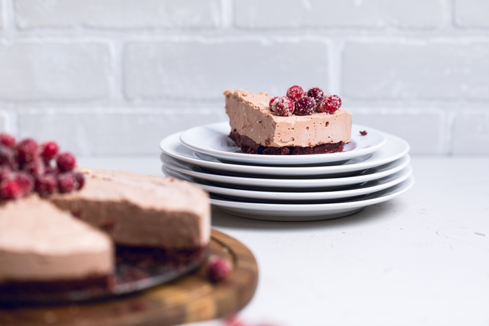 a slice of no bake vegan chocolate cheesecake on a stack of white plates.