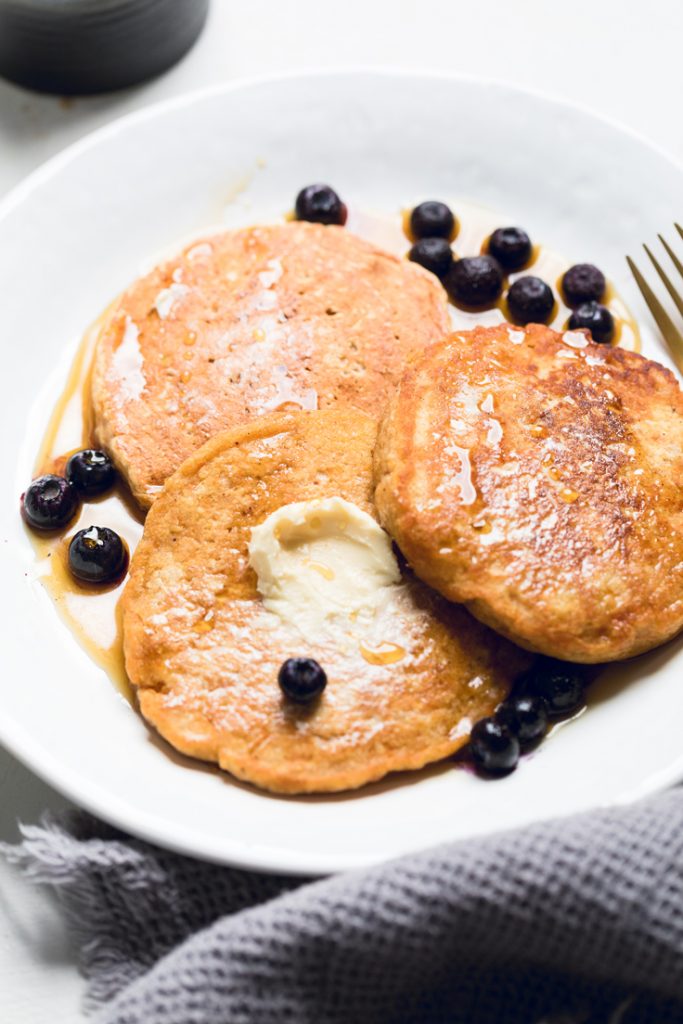 vegan sweet potato pancakes on a white plate with blueberries.