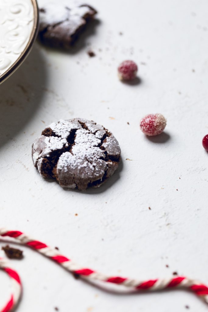One Vegan chocolate crinkle cookie with candied cranberries on a table.