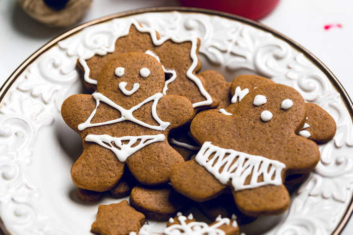 two vegan gingerbread cookies frosted to look like a man in woman in swimsuits on a plate.