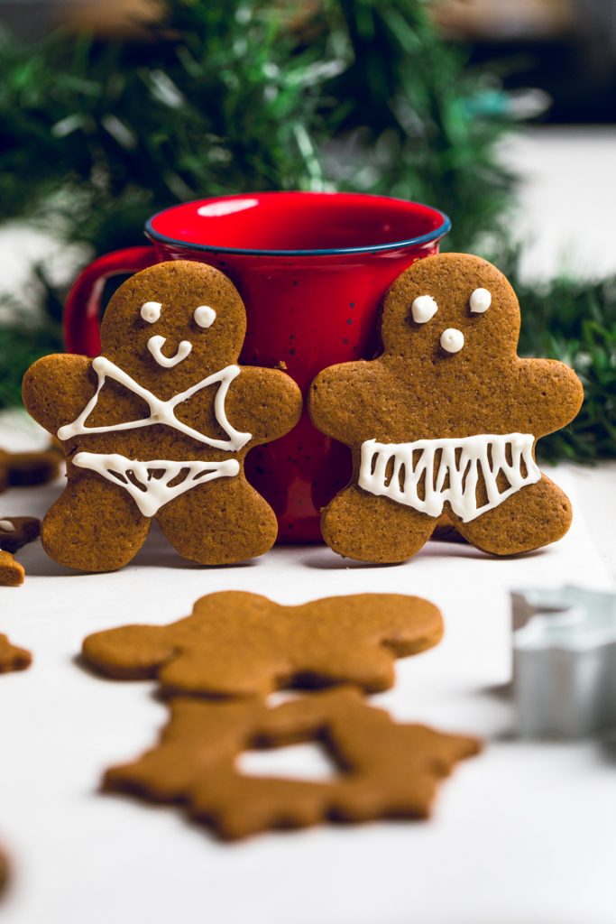 two vegan gingerbread cookies frosted to look like a man in woman in swimsuits.