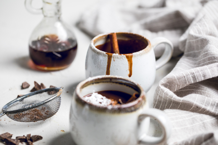 Two mugs of vegan maple syrup cinnamon and brown sugar hot chocolate.
