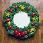 a wreath made with broccoli, peppers, and tomatoes with a bowl of ranch in the middle.