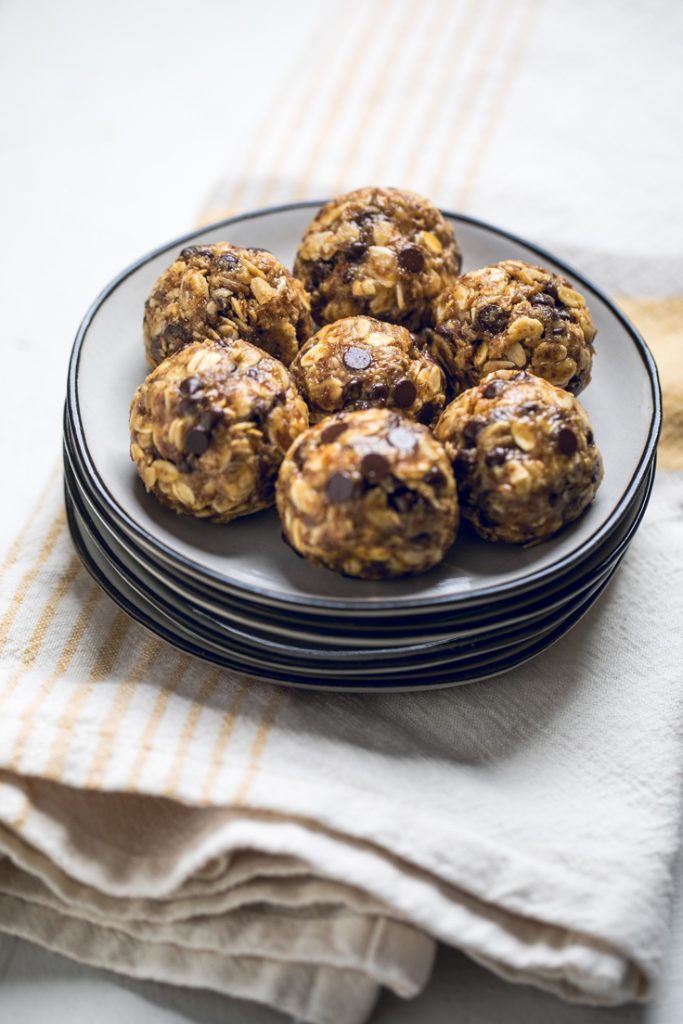 Seven vegan peanut butter chocolate energy balls on a small plate.