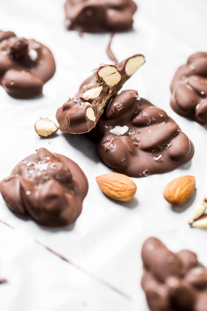 A vegan chocolate covered almond cluster broken in half.