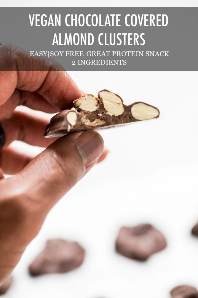 A hand holding vegan chocolate covered almond clusters with the recipe name overlayed.