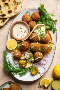 a plate of vegan falafels with tahini in a bowl on the side.
