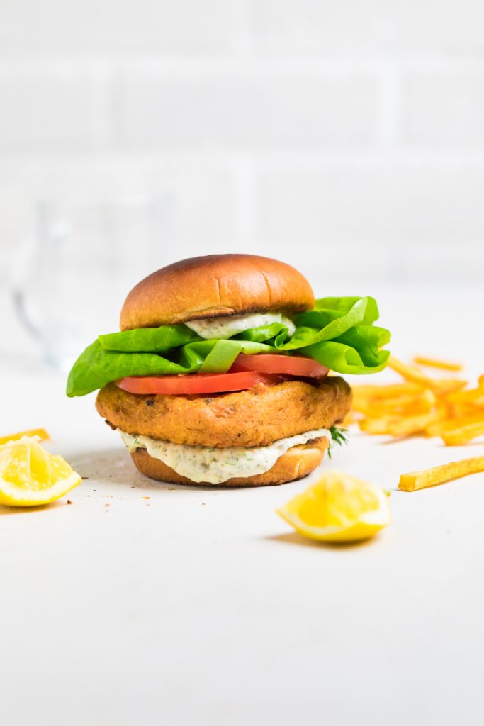 A vegan fish sandwich with tartar sauce lettuce and tomatoes. 