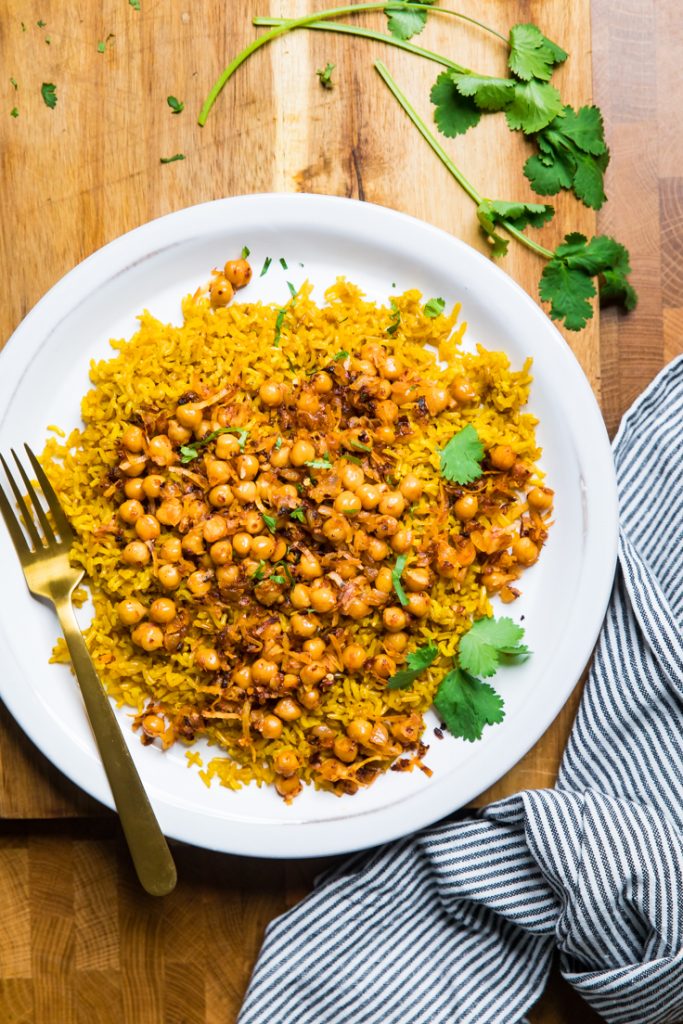 Vegan spicy coconut chickpeas over golden turmeric rice on a white plate. 