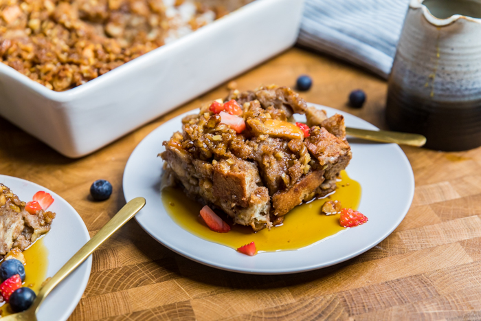 A serving of Vegan French toast casserole topped with fresh fruit and syrup.