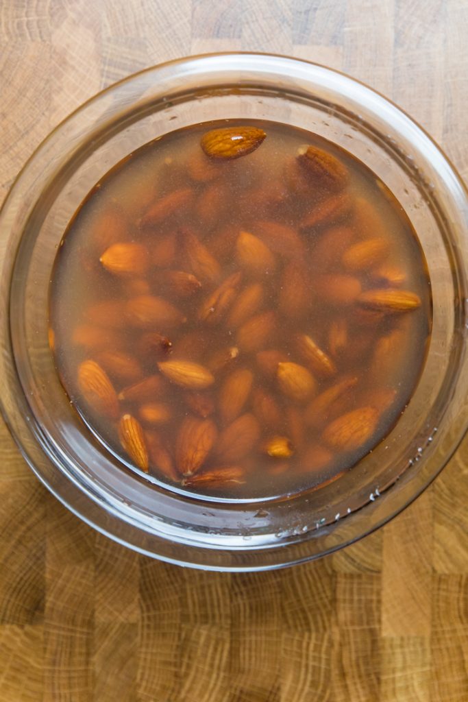 A bowl of water with soaked raw almonds.