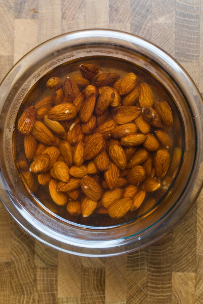 A bowl of raw almonds in water.