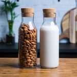 Two glasses side by side with almonds and almond milk.