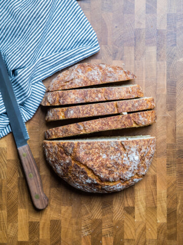 A loaf of vegan artisan bread with half sliced.