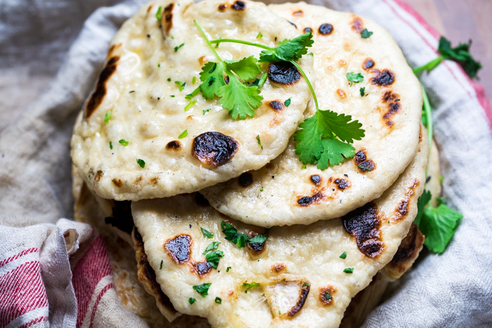 A plate of vegan naan topped with fresh cilantro.