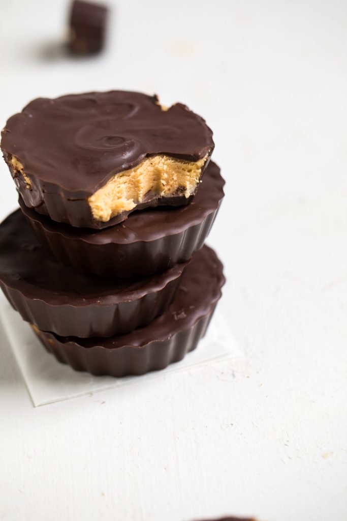 A stack of vegan peanut butter cups with a bite out of the top one.