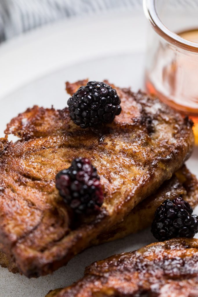 Stack of two pieces of chocolate vegan babka French toast topped with fresh blackberries.