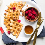 An overhead shot of a plate of vegan coconut flour waffles with fresh raspberries.