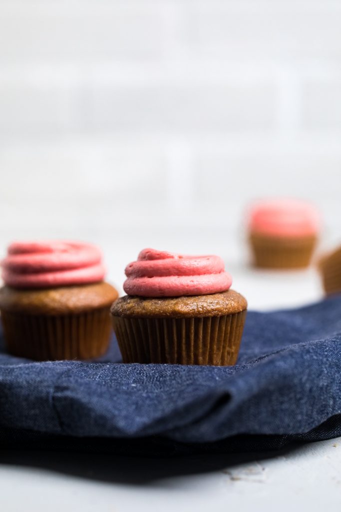Two dye free vegan strawberry cupcakes with vegan strawberry buttercream frosting.
