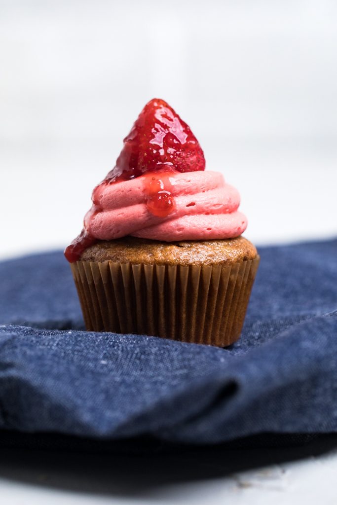 A dye free vegan strawberry cupcake atop a denim towel.