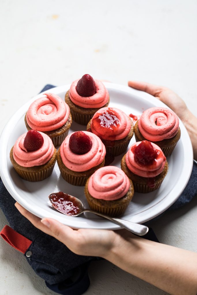 A plate of dye free vegan strawberry cupcakes with frosting. 