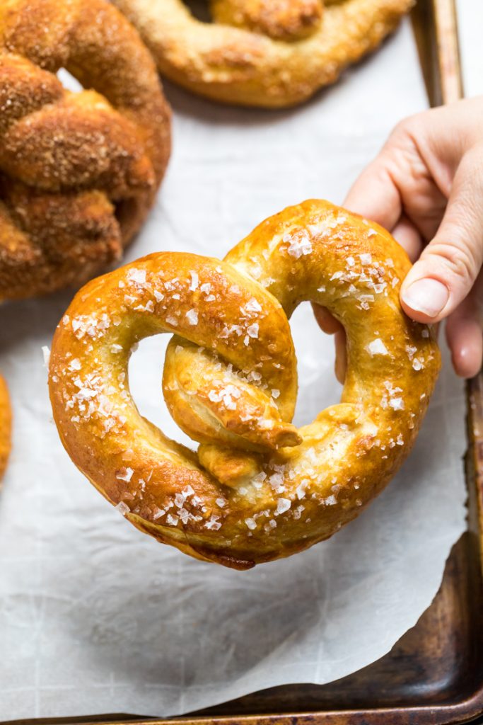 A hand holding a salted vegan soft pretzel.