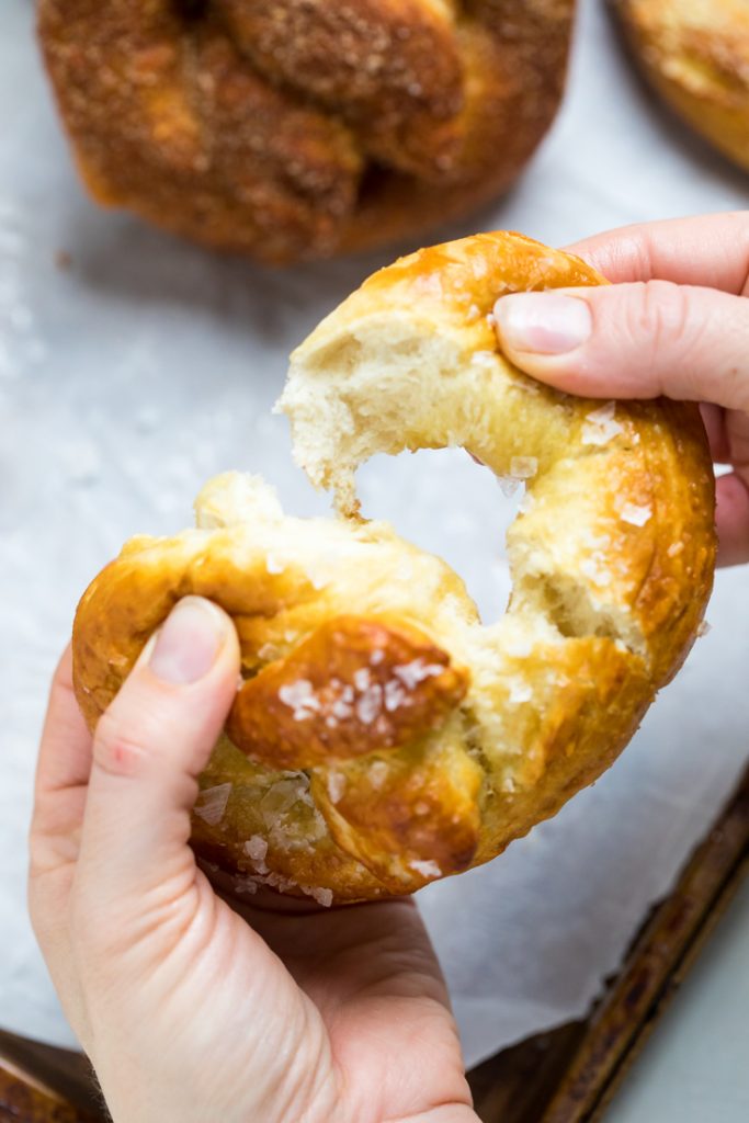 A vegan soft pretzel being pulled apart.