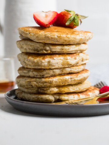 A plate of fluffy vegan pancakes stacked with syrup drizzling.