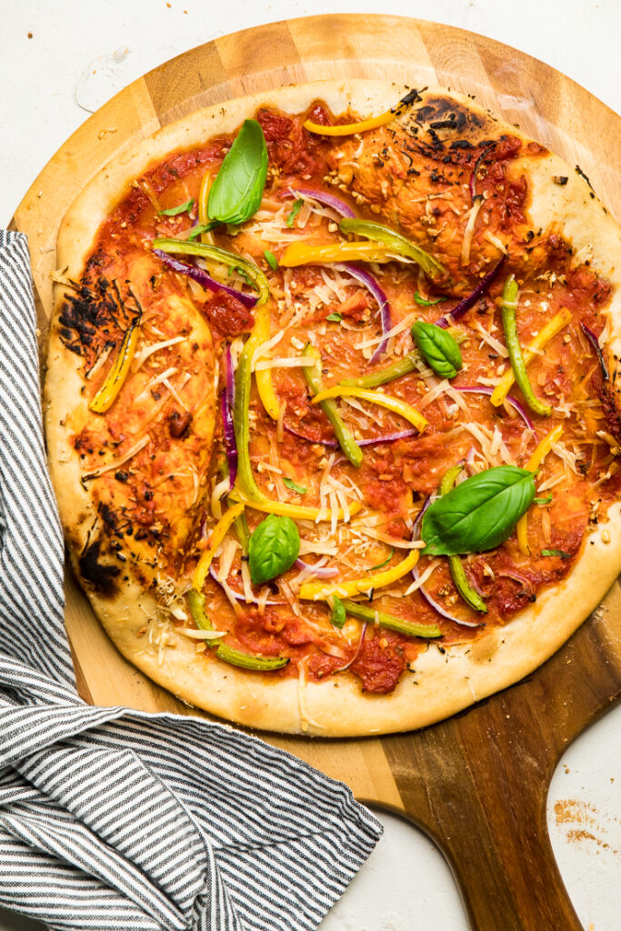 Easy 2 ingredient yeast free vegan pizza dough topped with peppers and basil.