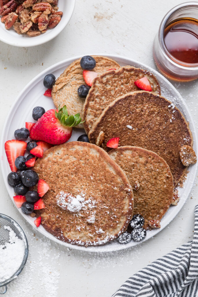 A plate of 3 ingredient vegan oatmeal pancakes with strawberries and blueberries. 