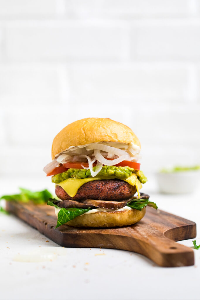 the best high protein vegan burger on a wooden bowl with vegan cheese and fresh toppings.