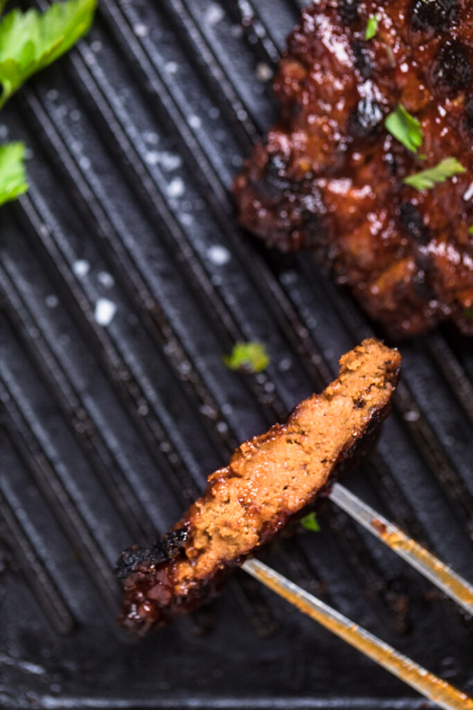 A close up of a piece of BBQ seitan chicken on a fork.