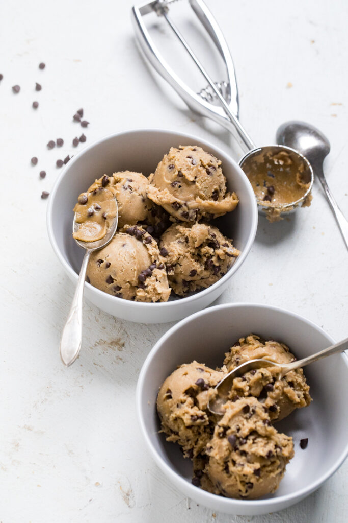 Two bowls with spoons with scoops of vegan edible cookie dough.