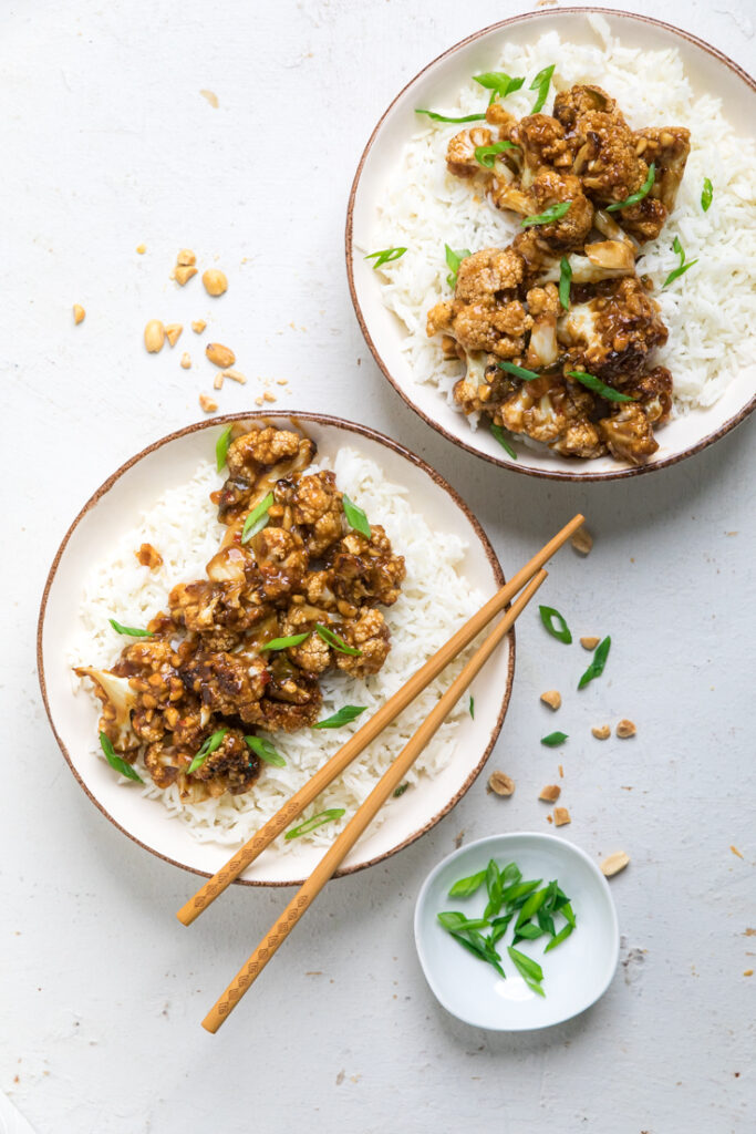 Two bowls of vegan kung pao cauliflower with rice.