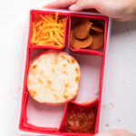 5 ingredient vegan pizza lunchables in a lunchbox tray being held.