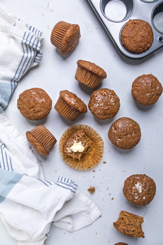 Maple cinnamon and brown sugar vegan zucchini muffins scattered across a table.