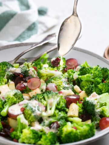 A spoon pouring dressing over easy vegan broccoli salad.