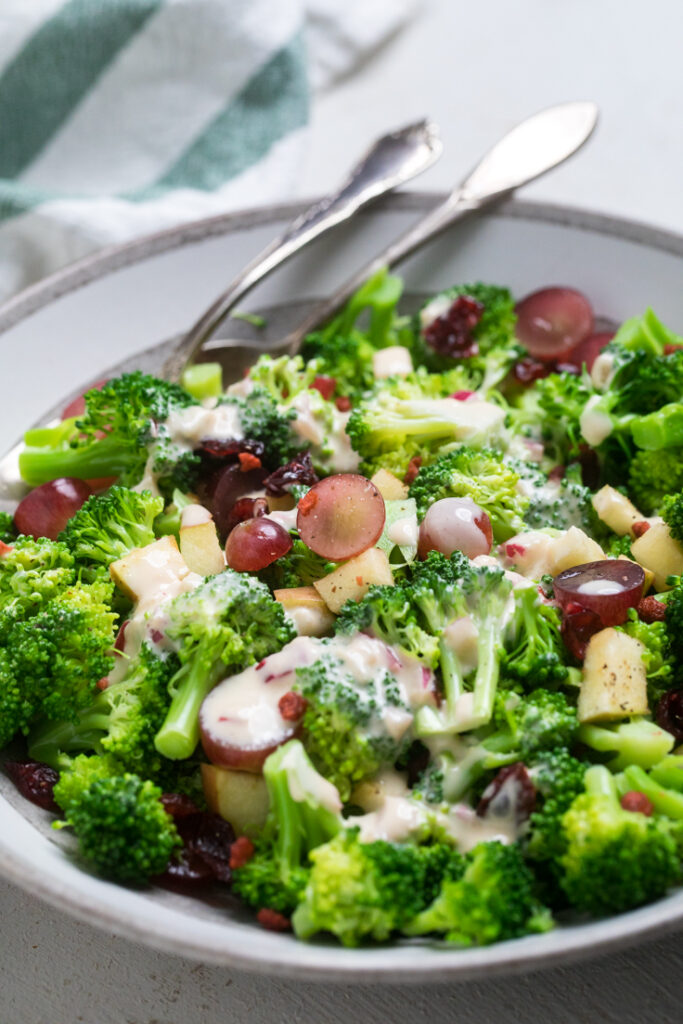 A bowl of easy vegan broccoli salad with extra salad dressing drizzled.